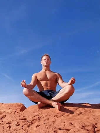 Man meditating on red rock